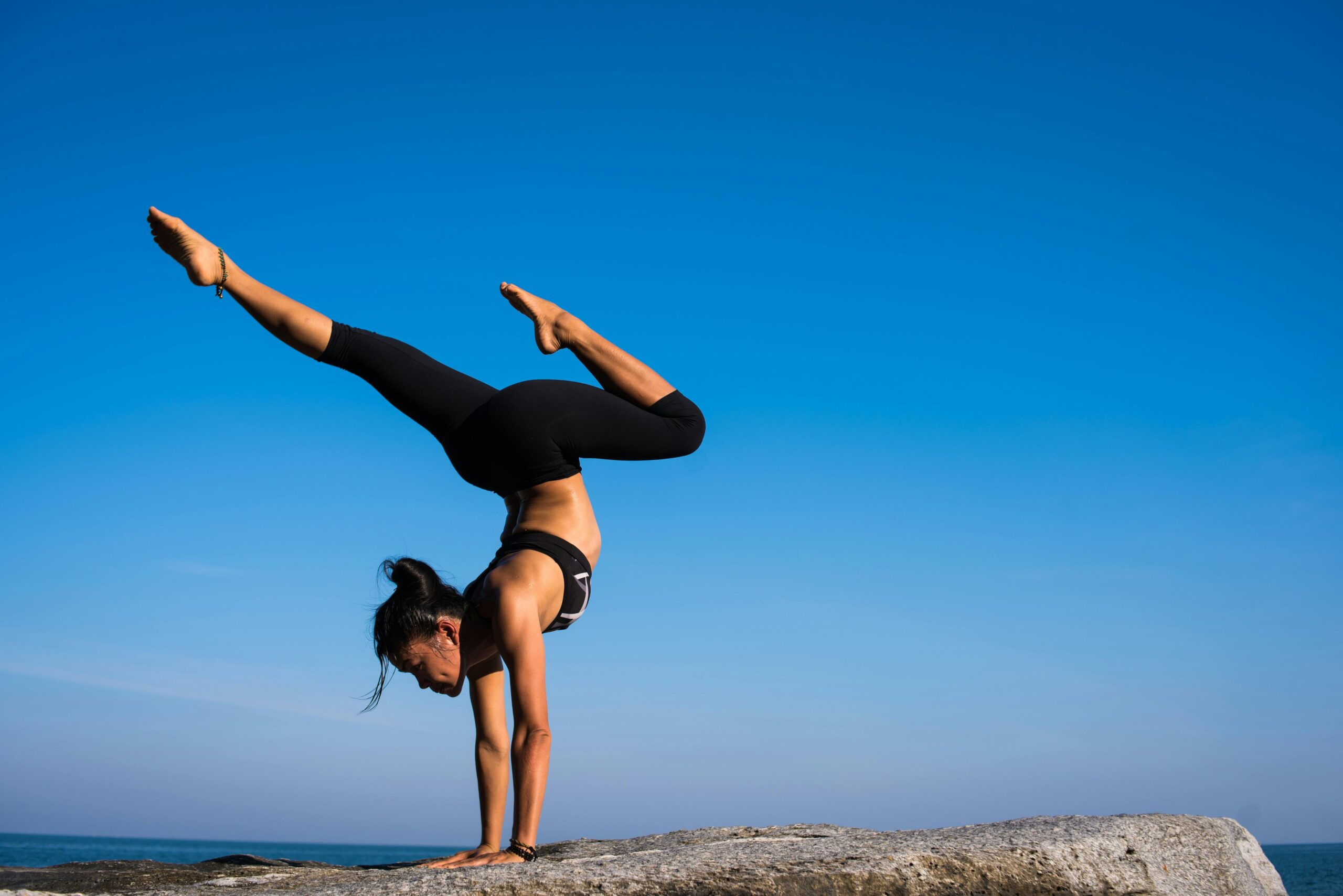a woman doing a handstand on a rock